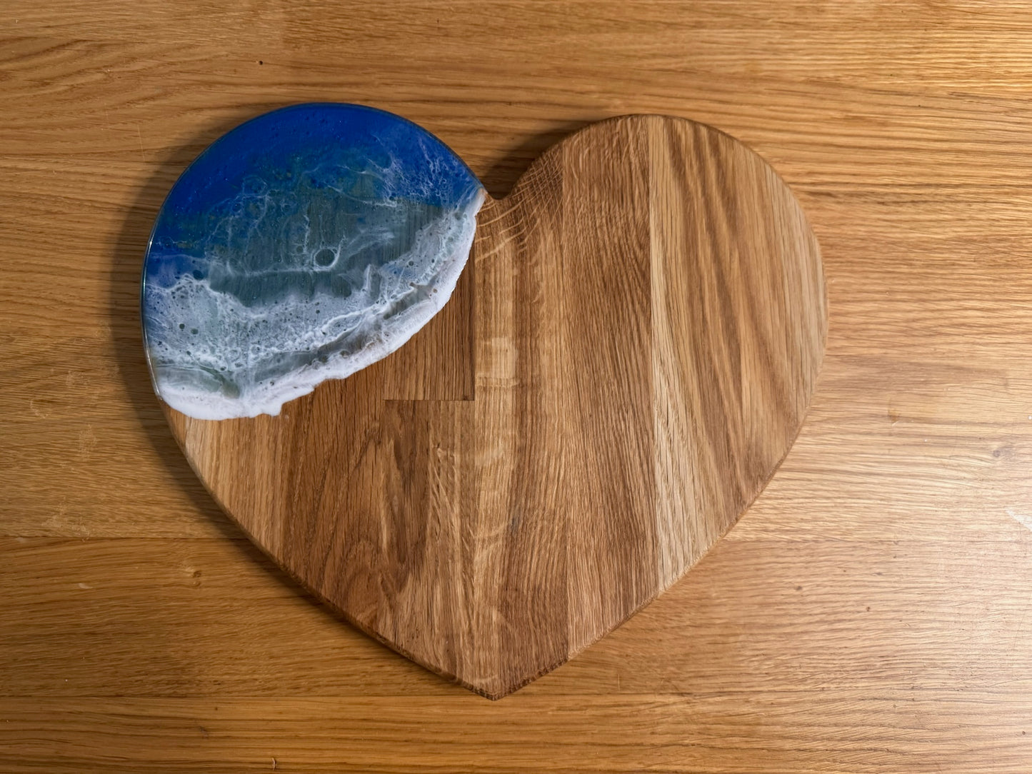 Heart-shaped oak serving board with blue resin ocean wave design, perfect for coastal home decor
