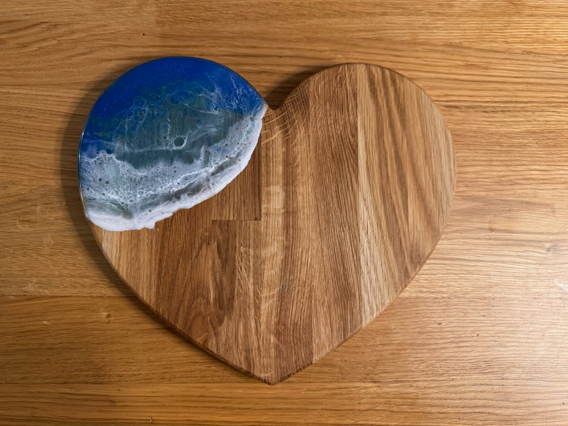 Heart-shaped oak serving board with blue resin ocean wave design, perfect for coastal home decor