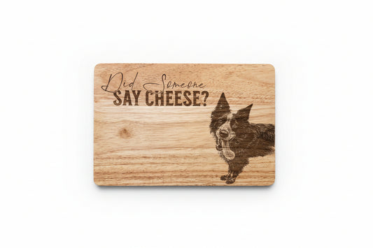 Wooden cutting board with a dog illustration and text 'Did someone say cheese?' on a wooden surface.