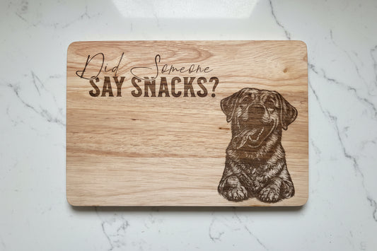 Wooden cutting board with a dog illustration and text on a marble surface